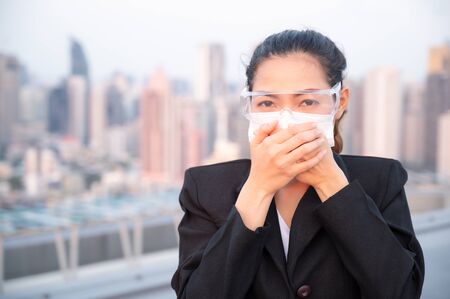 Asian business women have to use masks and goggles to protect against pollution from dust and prevent the infection from viruses spreading in the airの写真素材