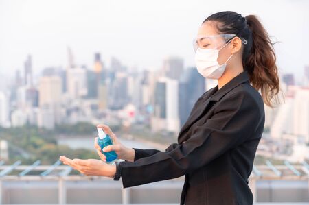 Asian business women have to use masks and goggles to protect against pollution from dust and prevent the infection from viruses spreading in the air with the introduction of preventive alcohol sprayの写真素材