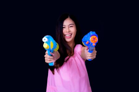 A beautiful Asian woman shows a gesture while holding a plastic water gun during the Songkran...