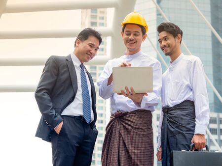 Young Burmese businessmen meet and talk about their business through Internet search, During working hours outside the officeの写真素材