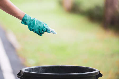 The woman wears rubber gloves to keep out dirt and germs while she keeps a used face mask, And were left in public areas without proper storageの写真素材