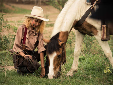 Cowgirl and the horse are deeply bonded to each other in love because of their distressed relationships in a wild outlawの写真素材