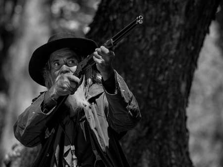 A senior cowboy is aiming the rifle at the attacker, While security surveillance in rural farm areasの写真素材