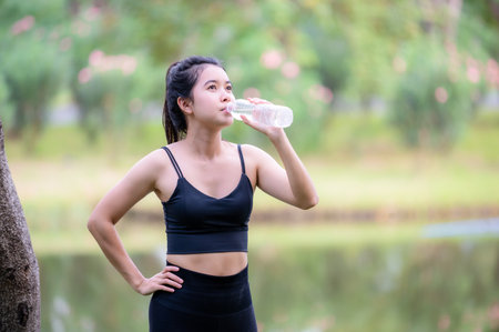 Beautiful Asian women drink water before warming up to keep their muscles flexible before jogging...