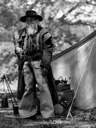 A senior cowboy standing with a gun to guard the safety of the camp in the western area