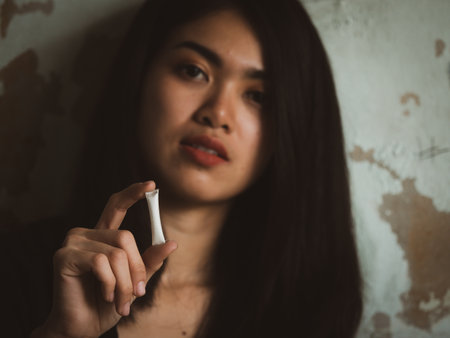 A young Asian teenage girl uses a plastic tube containing white drugs to sell to addicted customersの写真素材