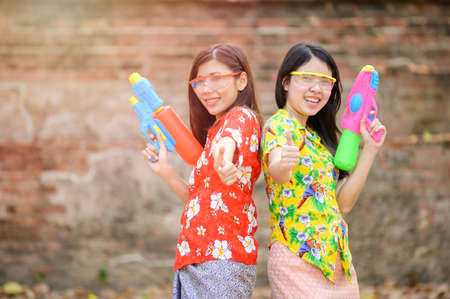 Beautiful Asian women hold plastic water guns at an ancient temple during Songkran, the most beautiful and fun water festival in Thailandの写真素材