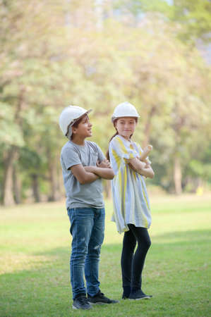 A half-Thai-Indian boy  and a mixed-Thai-European girl wearing a helmet holds a blueprint And expecting that in the future will be an engineer to build buildingsの写真素材