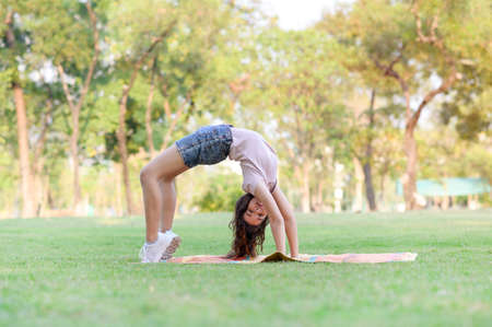 Half Thai-European girls exercising in gymnastics as part of their learning outside of school in the parkの写真素材