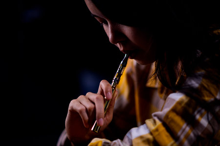 Teenage girl vaporize cannabis through a vaporizer containing cannabis oil in a tube after electrical heatingの写真素材