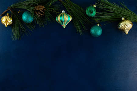 man wraps a handmade eco style christmas present in kraft paper and natural spruce branches on a blue wooden backgroundの写真素材