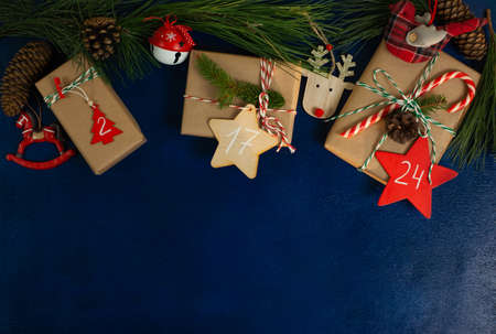 man wraps a handmade eco style christmas present in kraft paper and natural spruce branches on a blue wooden backgroundの写真素材
