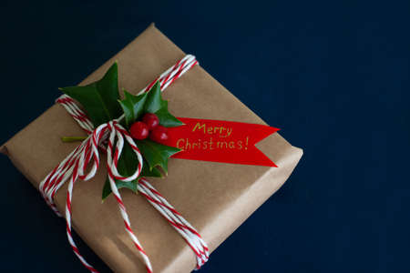 man wraps a handmade eco style christmas present in kraft paper and natural spruce branches on a blue wooden backgroundの写真素材
