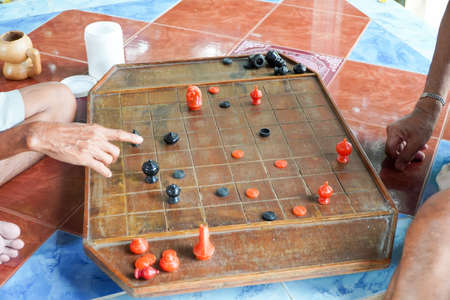 Two Asian men playing a game of chess in their backyard.