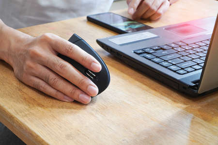 Hands are scrolling to find products and use the laptop. Online shoppingの写真素材