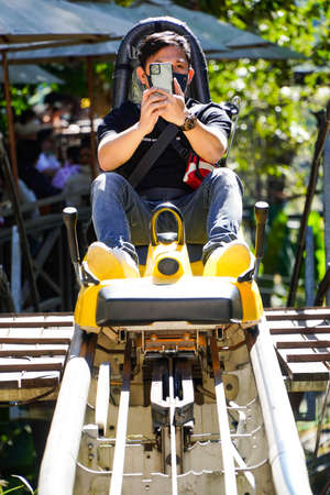Asian men enjoy a fun alpine roller coaster while enjoying a beautiful sunny day in the middle of nature.の写真素材