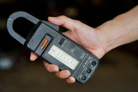 Male hand holding an analog clamp meter,concept of electric currentの写真素材