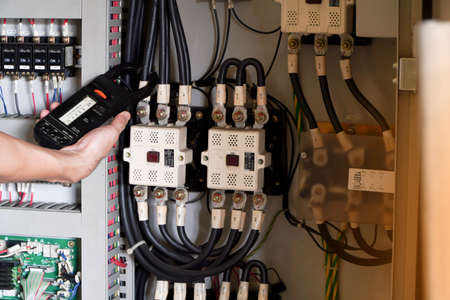 Electrician engineer work tester measuring voltage and current of power electric line in electical...