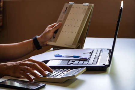 man busy paying bills online on computer calculating household finances or taxes on machine, female manage home family expenditures, using calculator, make payment on laptopの写真素材