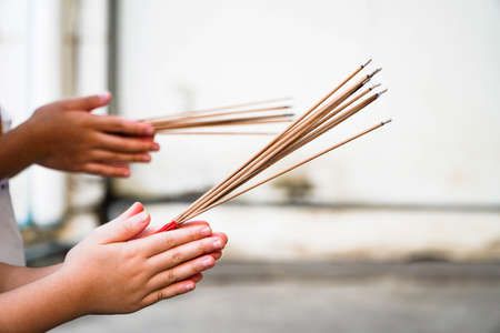 People hands lighting incense stick fire,Pay respect to buddha statueの写真素材