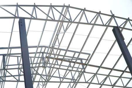 Structure of steel roof frame for building construction on sky background.