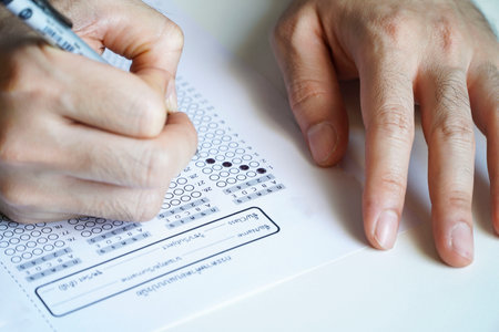 Students hold a pencil and write their choice on the answer sheet and math question sheet. college entrance examination studentsの写真素材