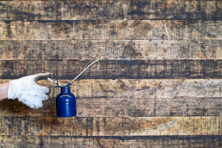 Maintenance worker holding oil cans on wooden floor,Lube oil can and used in industry or machinery lubricantsの写真素材