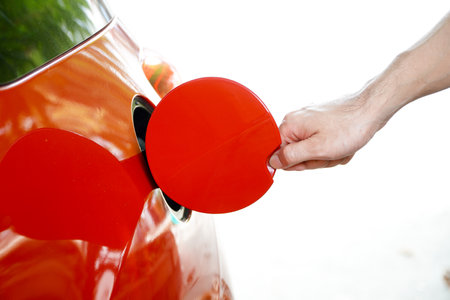 Man's hand opens electric car charger cover, idea of ââplanning to find a charging station before travelingの写真素材