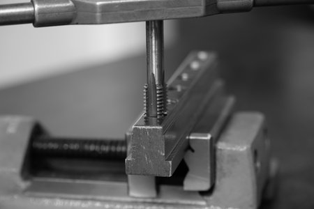 Spiral fluted steel tap bit making a thread in hole on mounted vise,Tapping the workpiece,machine...