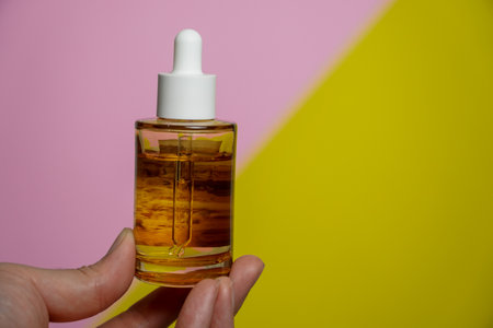 Man showing cosmetic serum bottle on pink and yellow background,Protector skin Treatment facial...