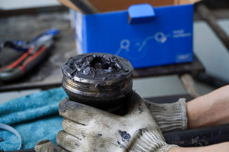 Asian mechanic changing axle and grease CV in front wheel drive car in garage,Macpherson suspension.