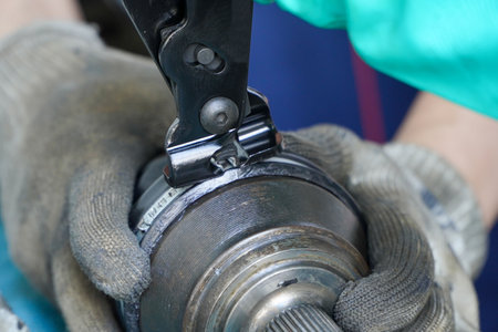 mechanic assembles a rubber cover for a car axle in a service center.Cv Clamp Tool And Cv Joint Boot...