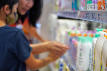 buyer in the store chooses shampoo on the shelves,Personal skin care products for children and adults.reads information about the goods on it.の写真素材