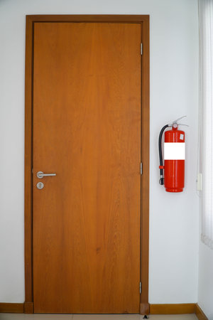 Fire extinguisher in the interior of a room with a wooden doorの写真素材