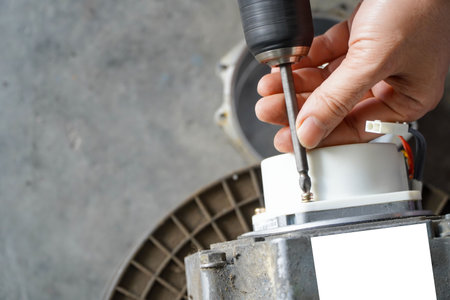 electric servo motor,Repairman using cordless screwdriver removing servo electric motor in workshopの写真素材