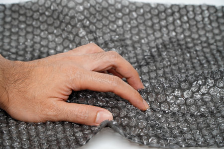 Angry man squeezing shockproof plastic pooping wrap with hands isolated on white background. stress reliefの写真素材