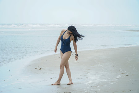 Portrait of a beautiful young Asian woman in a swimsuit walking at the beach.Asian woman summer travel outdoor concept.の写真素材