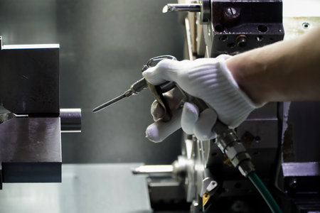 operator uses an air blow gun to clean the workpiece in the machine.Production of electric vehicle parts,5-axis CNC latheの写真素材