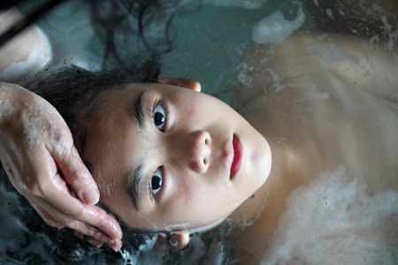 Mother washes beautiful woman's hair in bath with foam In Bathtub In Modern Bathroom Indoors.