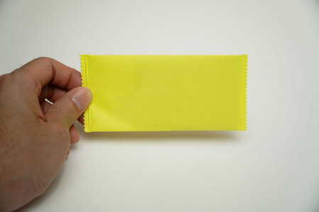 Hand holding a yellow condom isolated on white background. Safe sex concept.
