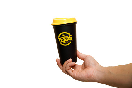 Bangkok, THAILAND November 25 â2023: Male hand holding black texas REUSABLE paper cup on black background.のeditorial素材