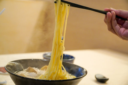Cooking Japanese noodle soup in a restaurant,Hands use chopsticks to pick up delicious ramen or noodles.の写真素材