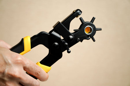 Hands of people punching hole of belt leather using the Metal hole puncher,