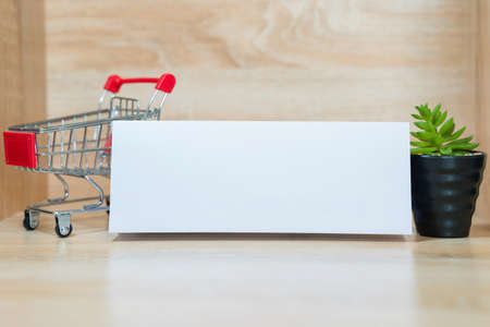 White paper for inserting text such as product name or seller's name information. In the background was a small cart and a small potted plant.の写真素材