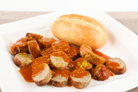 a curry sausage with roll on a plateの写真素材