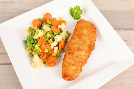 fried fish with vegetables on a plateの写真素材