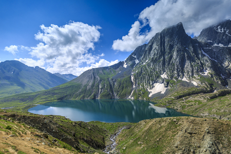 beautiful lake side with reflection of blue sky and white puffy clouds on the lake , mountains aroundの写真素材