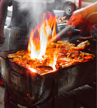man roasting chicken in a barbecue fire in winter eveningの写真素材