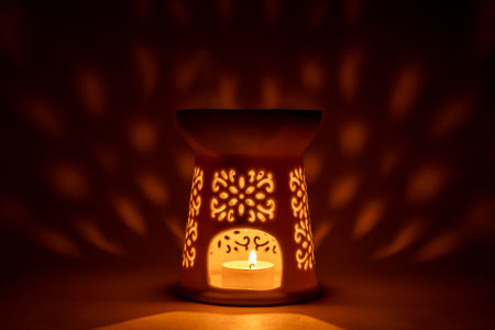 White ceramic candle lamp with a burning tea-light inside. Beautiful soft light reflections on the background, cozy and atmospheric interior photo.の写真素材