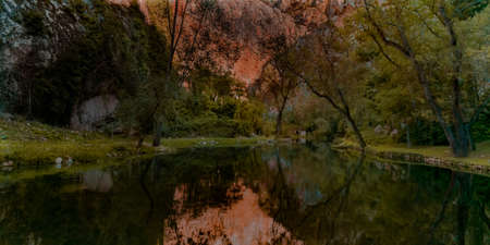 landscape of a lake and mountains with a small house in the background in autumn